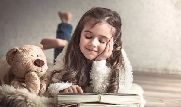 Kleines Mädchen Liest Ein Buch Mit Einem Teddybär Auf Dem — Stockfoto