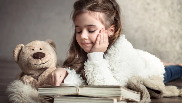 Kleines Mädchen Liest Ein Buch Mit Einem Teddybär Auf Dem — Stockfoto