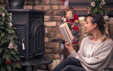 Kız şömine, eve geri kalan kavramı yakın rahat bir ev atmosferde bir kitap okuma