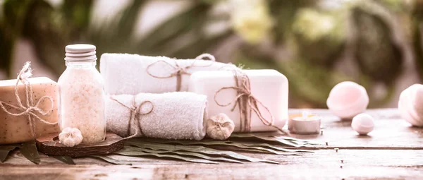 Spa handmade soap with white towels and sea salt, the composition of the tropical leaves with a candle, wooden background with space for text, concept of Spa and relaxation for the body