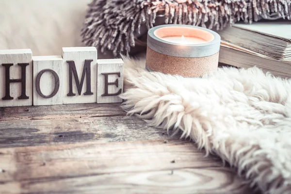 stock image Cozy still life on a wooden background with details in the interior, and wooden letters with the inscription Home and a big beautiful candle, the concept of comfort and home style