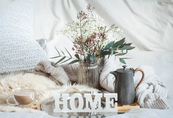 Home spring still life with a cup of coffee and a teapot on the background of the bed and a wooden inscription home