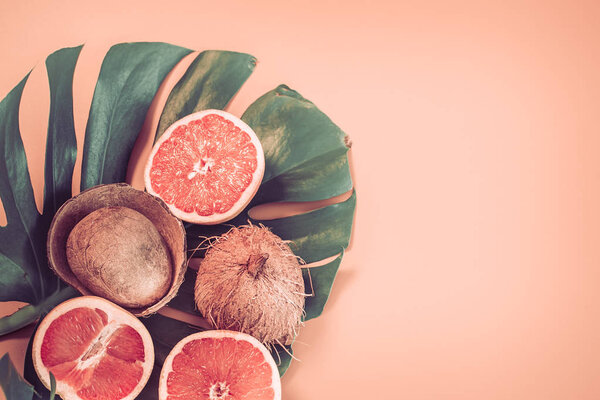 Colorful summer, tropical leaves and coconut fruits with grapefruit on a colored background.