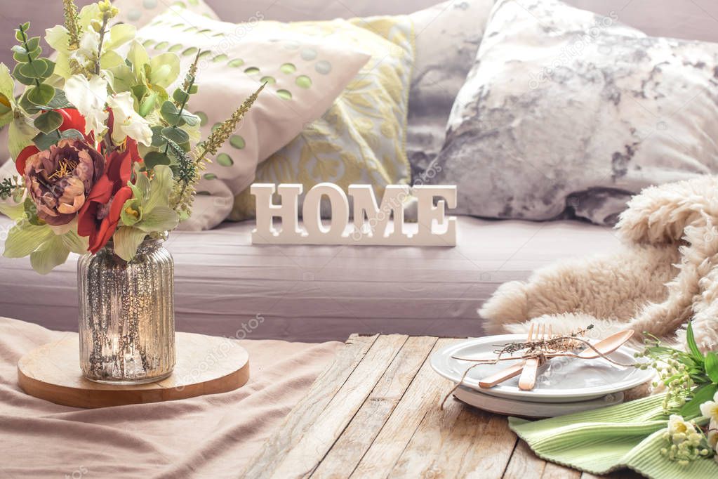 Still life spring interior with decor items in the home living room and wooden letters with the inscription Home.