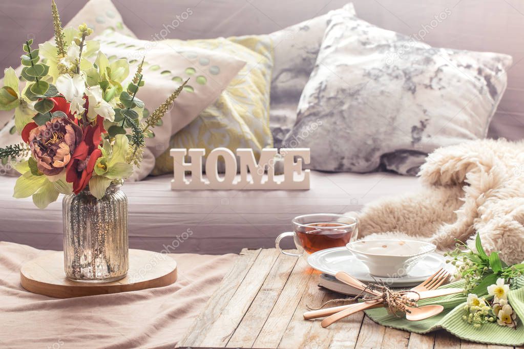 Still life spring interior with decor items in the home living room and wooden letters with the inscription Home.