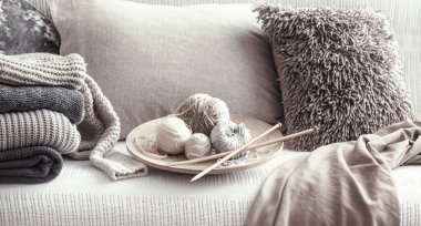 Antika ahşap örgü iğneleri ve konu için örgü yastıklar ve kazak ile rahat bir kanepe. Still life fotoğraf. Konfor kavramını