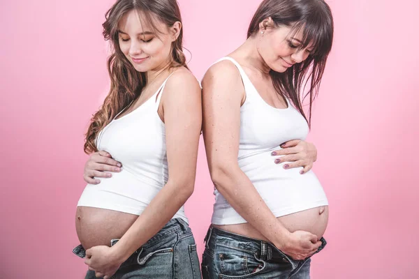 出産の概念 Jindes と女性の友情 色付きの背景に白い シャツで開いておなかと つの美しい妊娠中の女性 — ストック写真