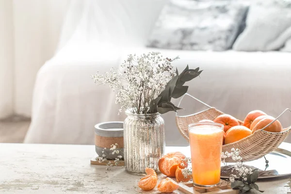 Freshly-grown organic fresh orange juice in the interior of the house, with a turquoise blanket and a basket of fruit