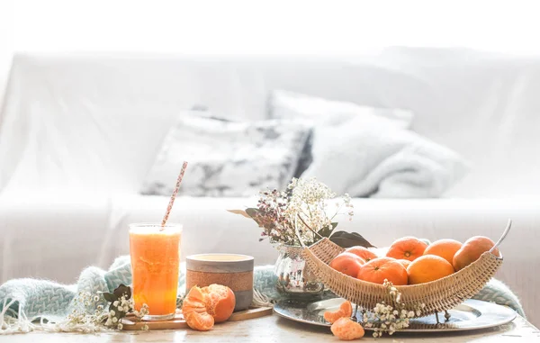 Freshly-grown organic fresh orange juice in the interior of the house, with a turquoise blanket and a basket of fruit
