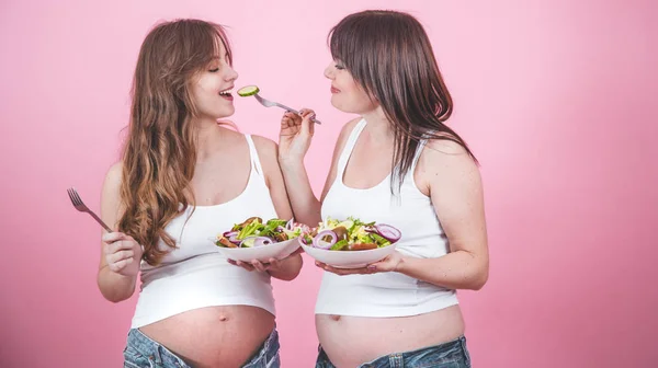 Annelik kavramı, taze salata yemek iki hamile kadın — Stok fotoğraf