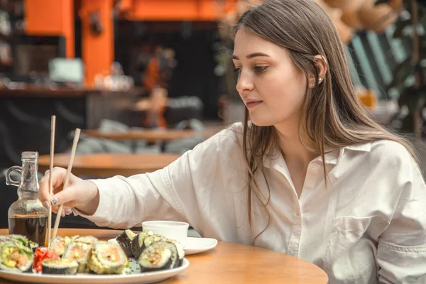 Mujer joven comiendo y disfrutando de sushi fresco — Foto de Stock