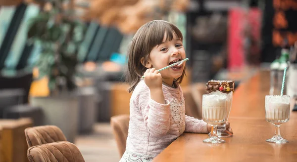 Очаровательная смешная маленькая девочка пьет молочный коктейль — стоковое фото