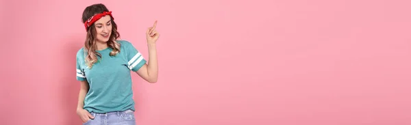 Красивая молодая девушка в зеленой футболке показывает палец на розовый — стоковое фото