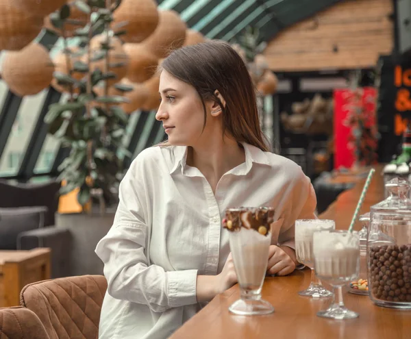 Hermosa chica joven bebiendo chocolate con leche cóctel en un café — Foto de Stock