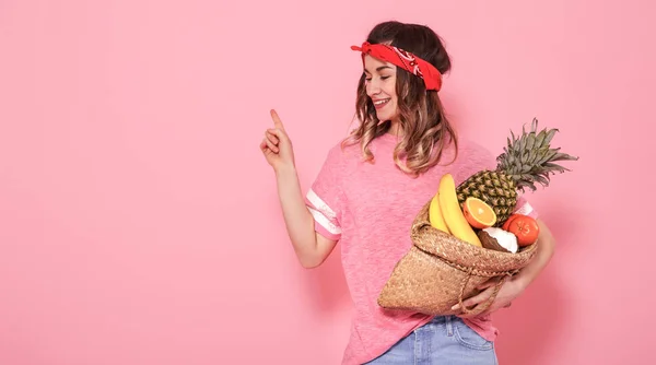 Портрет девушки с сумкой с фруктами, изолированными на розовой спине — стоковое фото