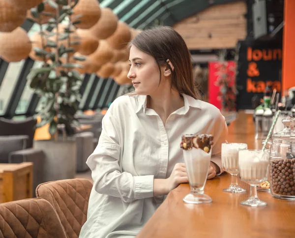 Hermosa chica joven bebiendo chocolate con leche cóctel en un café — Foto de Stock