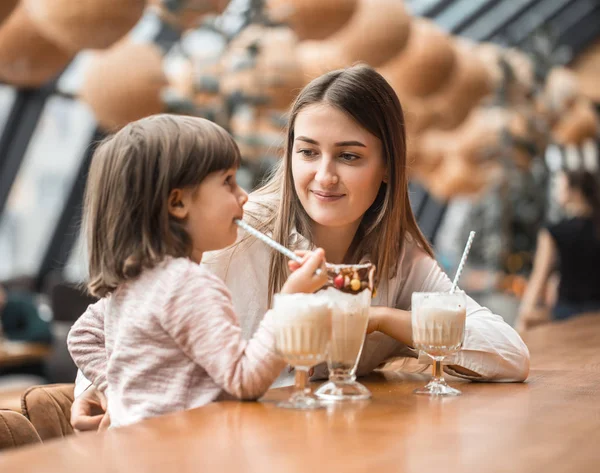 Feliz joven madre con hijos bebiendo un batido — Foto de Stock