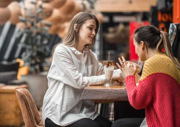 Dos mujeres felices están sentadas en un café, bebiendo batidos. , — Foto de Stock
