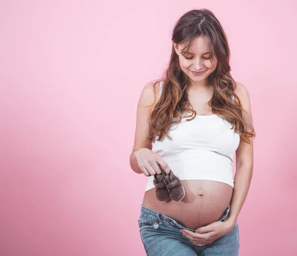 Concept maternité, femme enceinte avec des babouches dans les mains — Photo