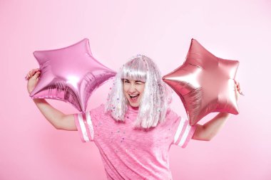 Gümüş saçlı kız pembe bir gülümseme ve duygu verir. Genç kadın veya balonlar ve konfeti ile genç kız