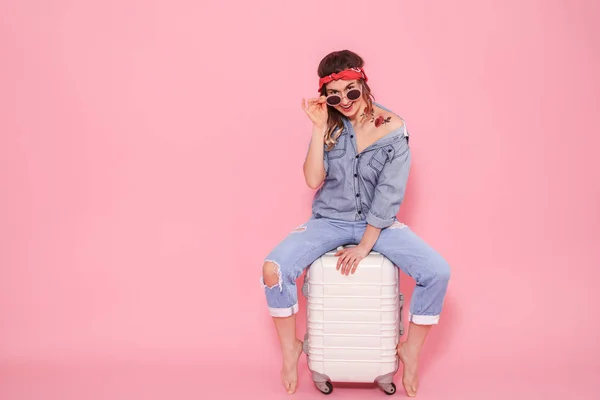 Портрет девушки с чемоданом на розовом фоне — стоковое фото