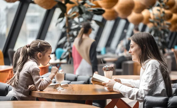 Feliz joven madre con niños sentados en la mesa y hablando en el restaurante — Foto de Stock