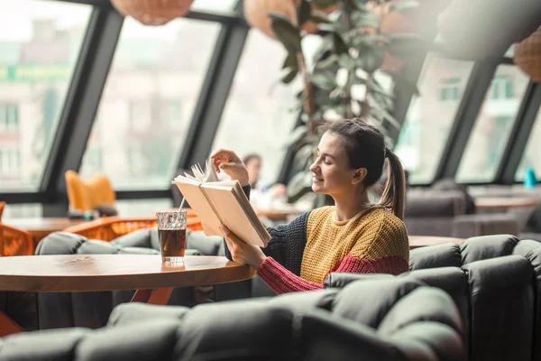 Joven hermosa mujer en suéter naranja lectura libro interesante en la cafetería — Foto de Stock