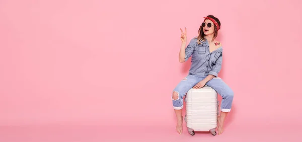 Beautiful young girl in denim shirt with water decal tattoo flowers sticker smiling and sitting on suitcase — Stock Photo, Image