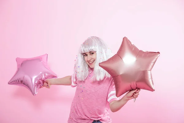 Funny Girl aux cheveux argentés donne un sourire et une émotion sur fond rose. Jeune femme ou adolescente avec ballons et confettis — Photo