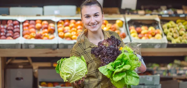 Süpermarkette bir kadın. Güzel genç kadın bir süpermarkette alışveriş ve taze organik sebzeler satın — Stok fotoğraf