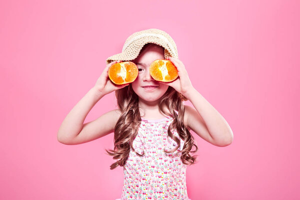 Смешная маленькая девочка с цитрусовыми фруктами на цветном фоне

