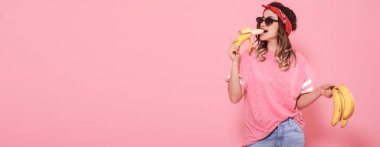 Güzel genç kız pembe tişört ve seksi muz tutan gözlük