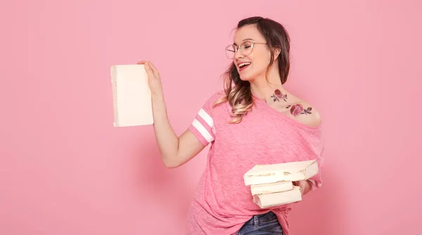 Портрет девушки с пачкой книг на розовом фоне — стоковое фото