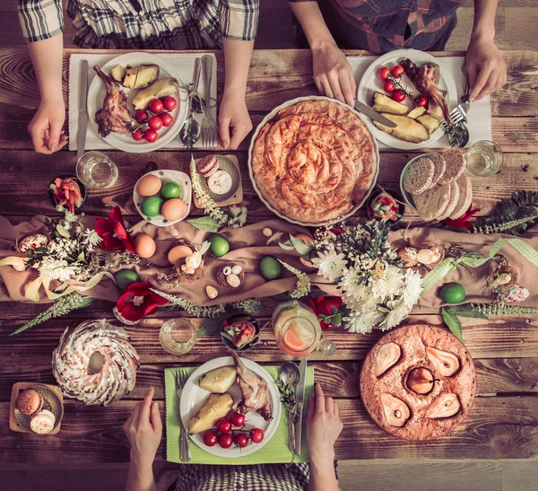 Amigos de vacaciones o familiares en la mesa de vacaciones con carne de conejo, verduras, pasteles, huevos, vista superior . — Foto de Stock