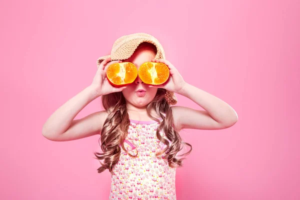 Смешная маленькая девочка с цитрусовыми фруктами на цветном фоне — стоковое фото
