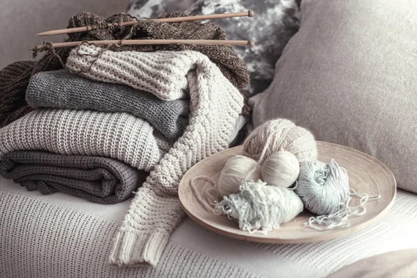 Aiguilles et fils à tricoter en bois vintage pour tricoter sur un canapé confortable avec des oreillers et des pulls — Photo