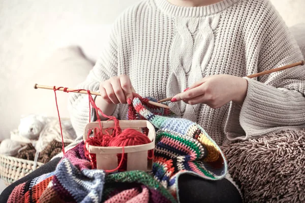 Mulher tricota agulhas de tricô no sofá — Fotografia de Stock