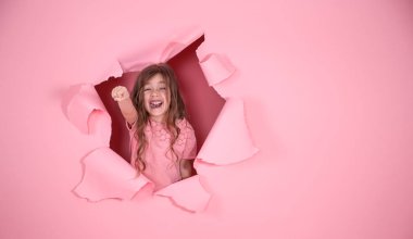 pembe arka planda süper kahraman oynayan küçük kız