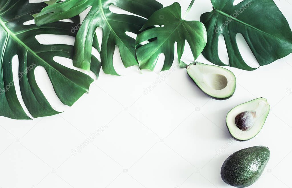 Avocado with tropical leaves on white background