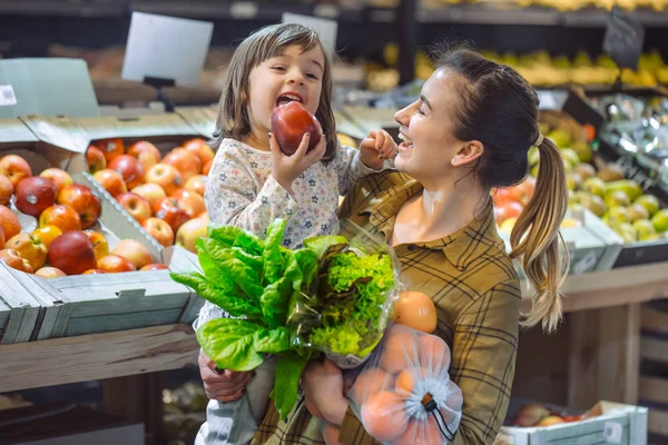 Aile süpermarket. Güzel genç anne ve küçük kızı gülen ve gıda satın.