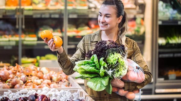 Süpermarkette bir kadın. Güzel genç kadın bir süpermarkette alışveriş ve taze organik sebzeler satın — Stok fotoğraf