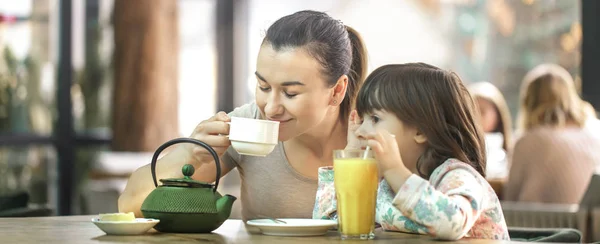 Mamá y su hijita están tomando té en un café. — Foto de Stock