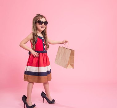 Küçük kız renkli bir arka plan üzerinde bir fashionista olduğunu