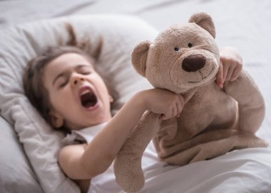 Oyuncak ile yatakta küçük sevimli kız