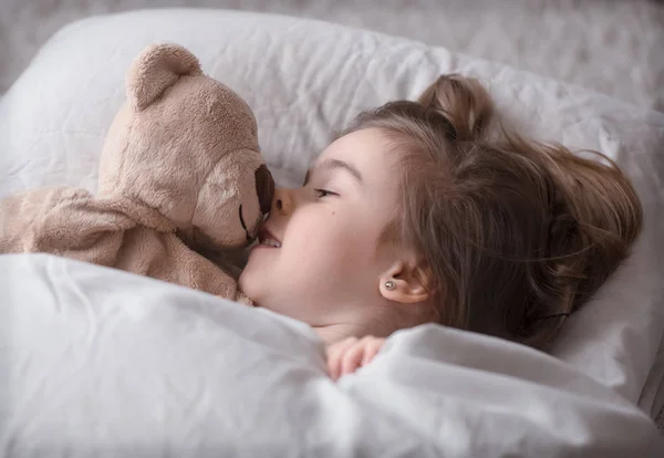 Kleines süßes Mädchen im Bett mit Spielzeug — Stockfoto