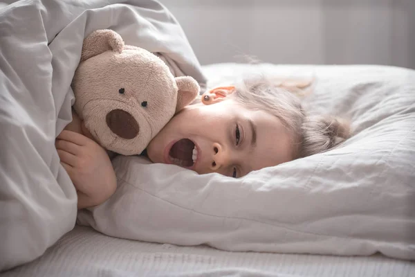 Kleines süßes Mädchen im Bett mit Spielzeug — Stockfoto