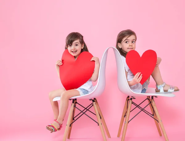 Две маленькие девочки с сердцем на цветном фоне — стоковое фото