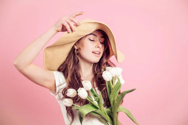 Дівчина в капелюсі і тюльпанах на кольоровому фоні — стокове фото