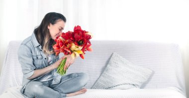 Young girl with a bouquet of tulips in the living room