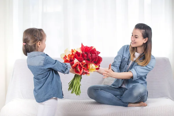 День Матери. Маленькая дочь с цветами поздравляет свою мать — стоковое фото
